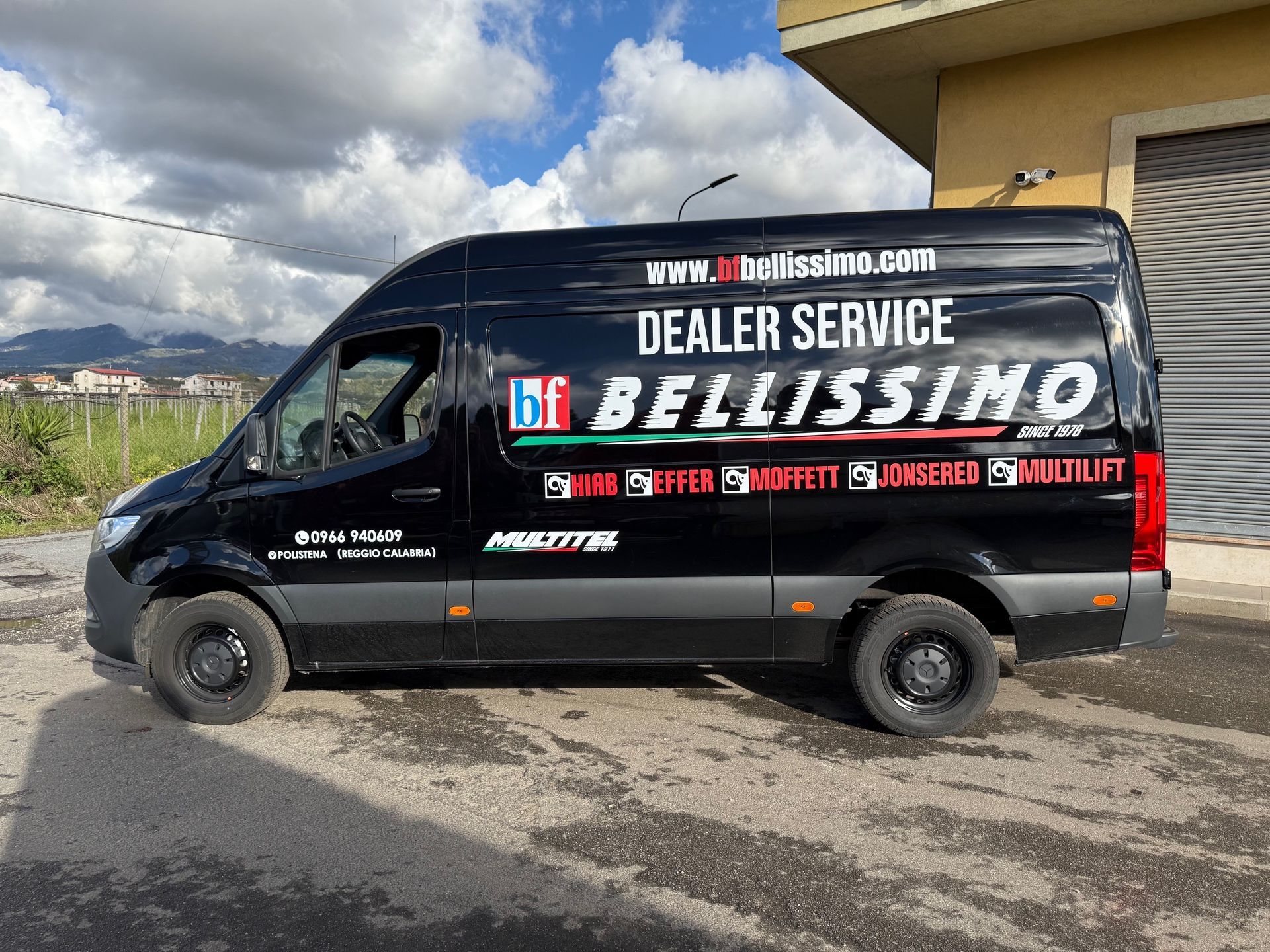 A black van is parked in front of a building.