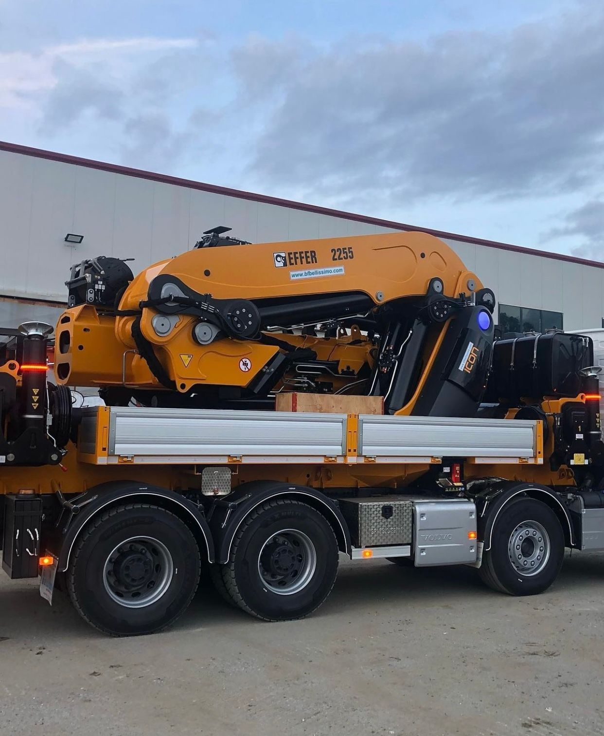 A large yellow crane is parked in front of a building