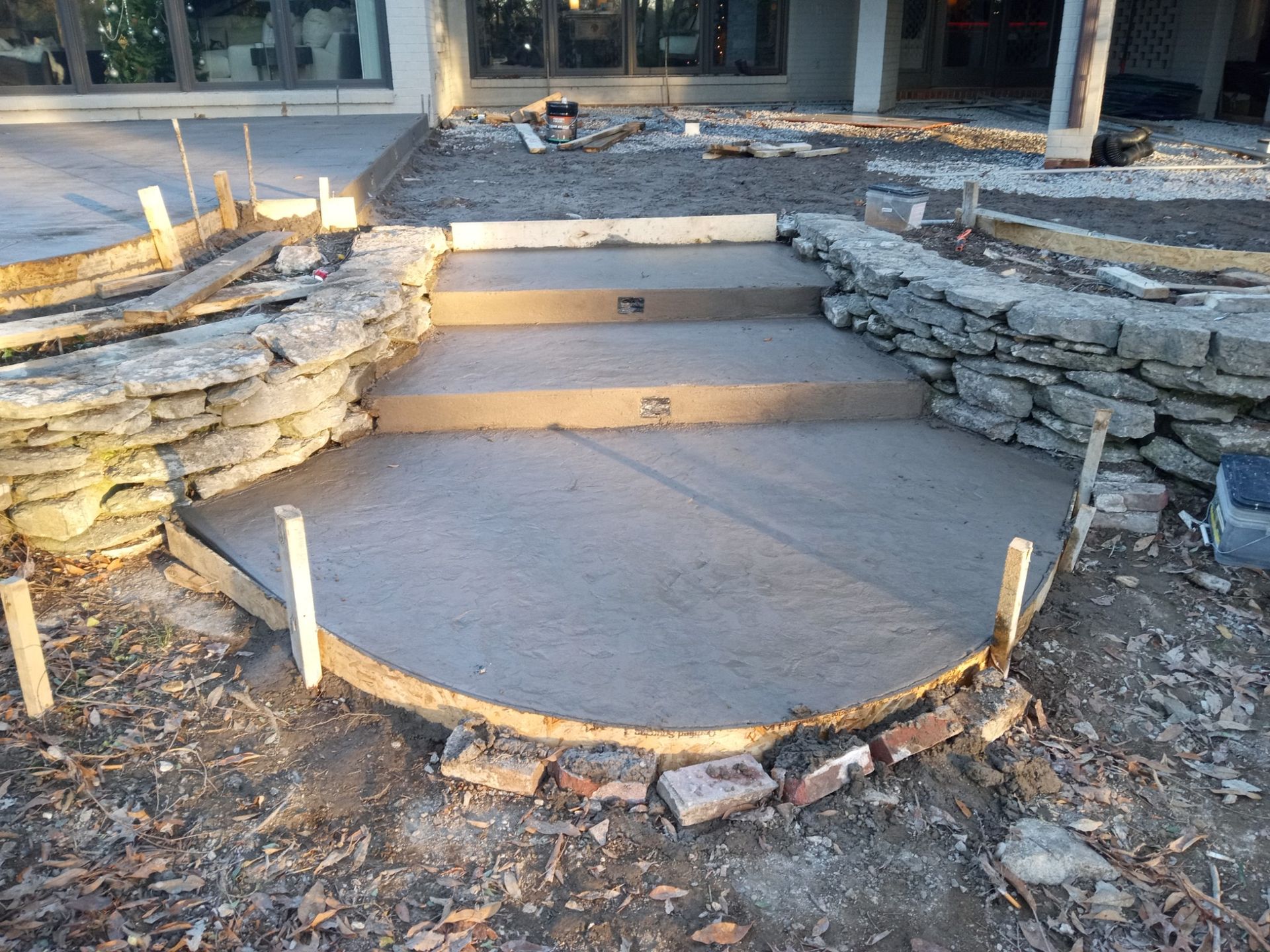 concrete steps and a curved patio area with stone retaining walls