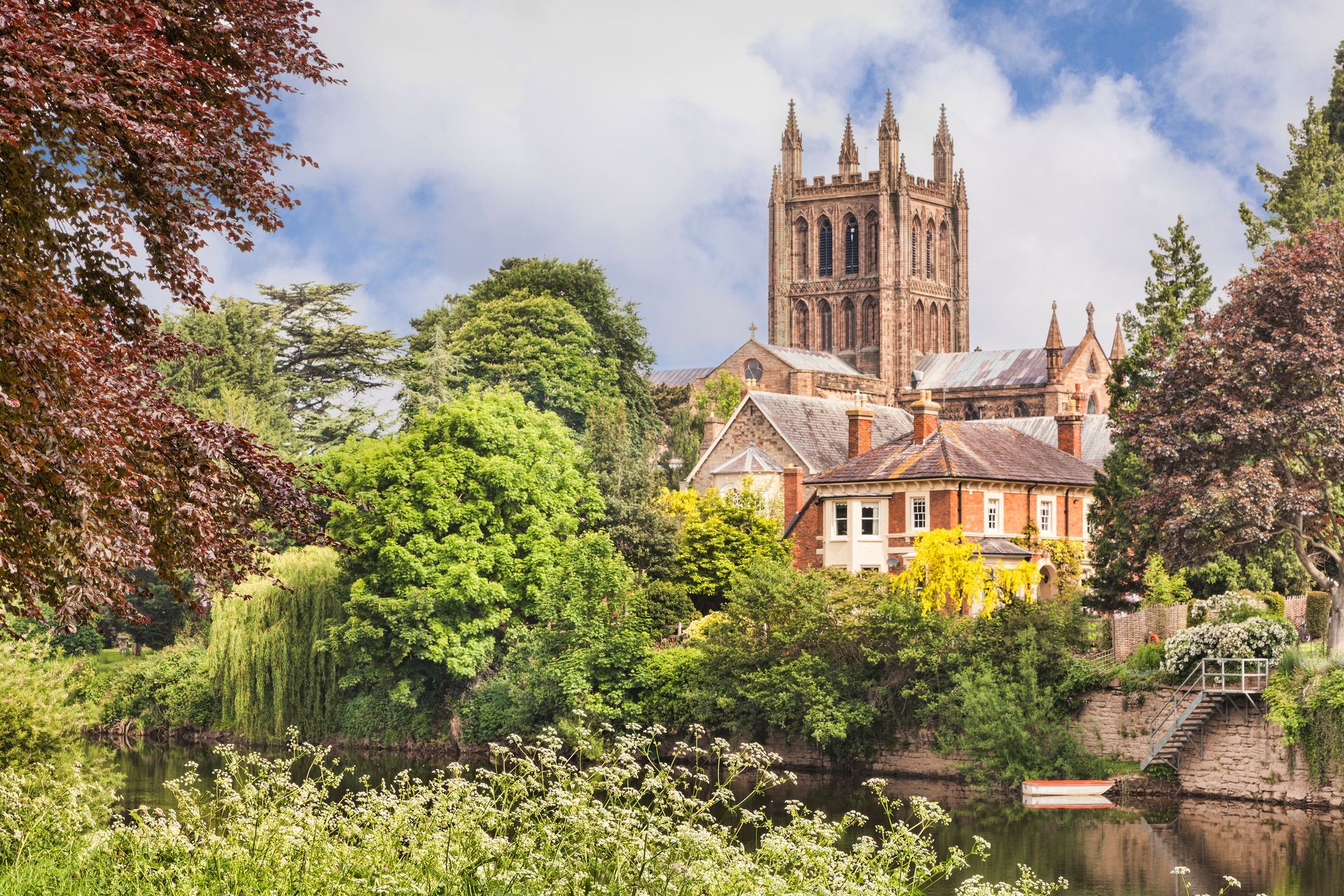 A stunning view across the River Wye, Herefordshire towards the tower of Hereford Cathedral in the background. Georgian period town houses are situated between the lush trees and cathedral.