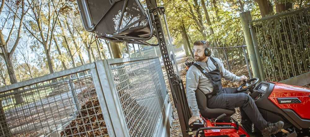 Un uomo su un quad rosso vicino a una recinzione e a un cancello in una zona boschiva all'aperto.