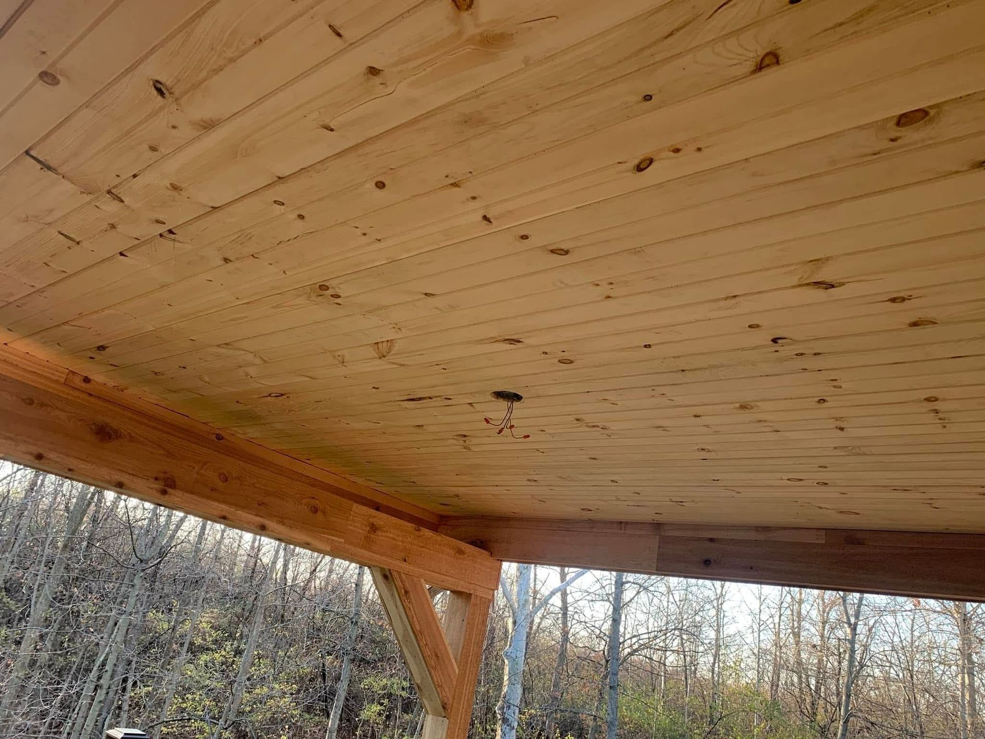 Wooden planks forming a ceiling, with small holes and a supporting beam visible.