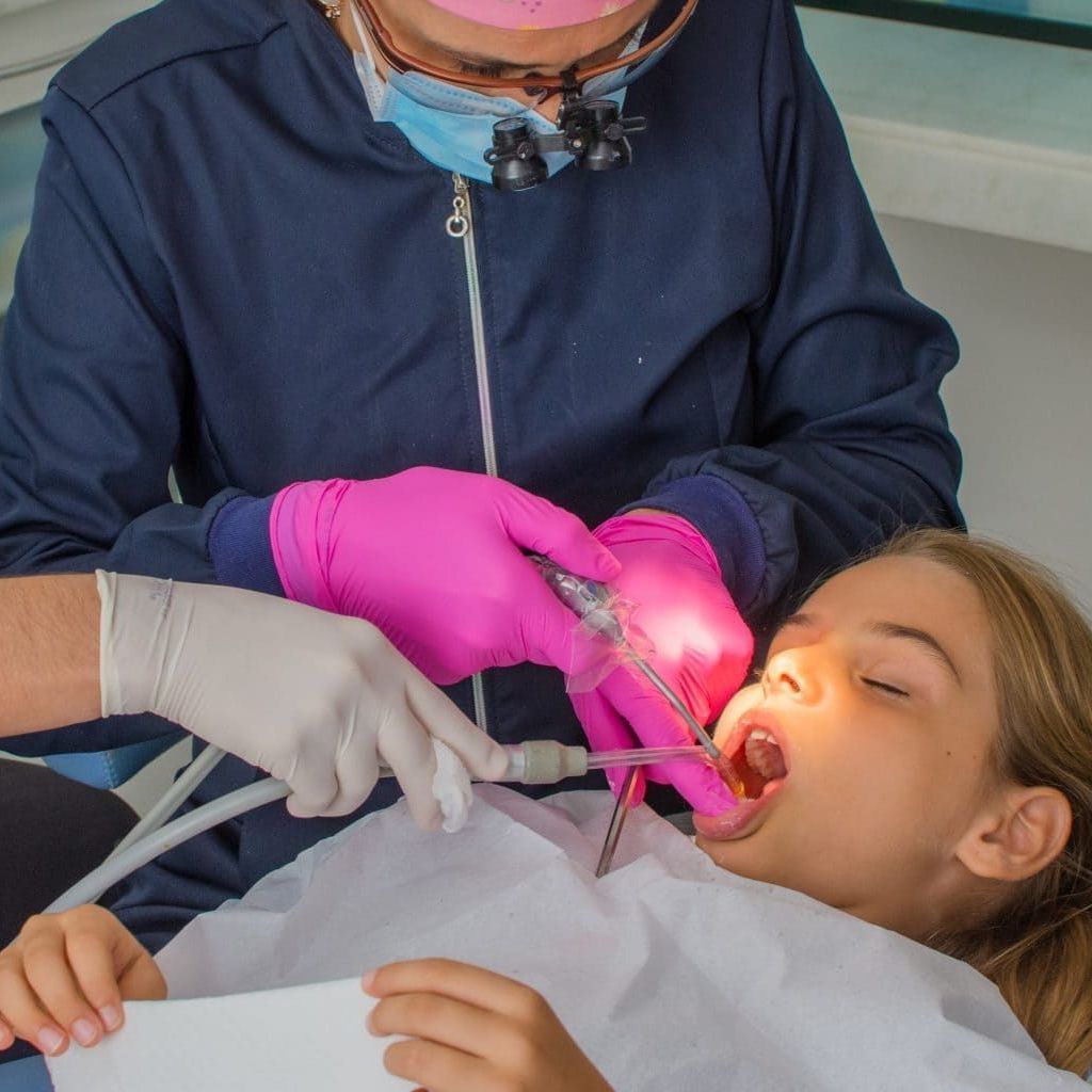 A girl is getting her teeth examined by a dentist