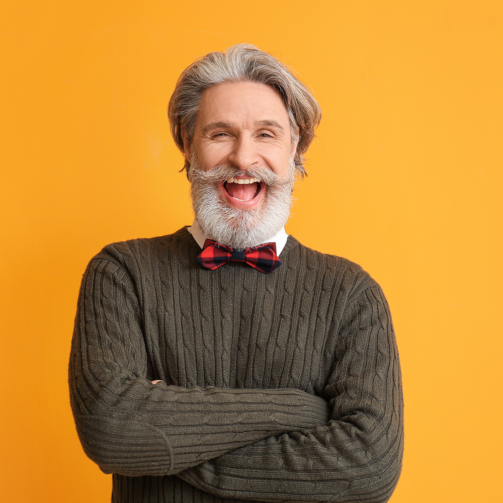 older gentleman standing smiling showing off his teeth
