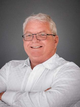 Smiling man in a white shirt and glasses against a gray background