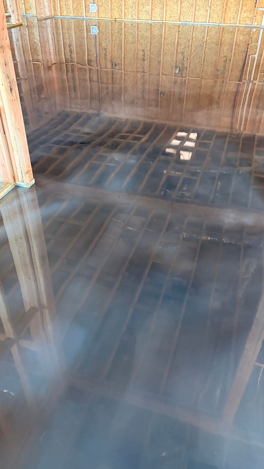 Interior of a building under construction, flooded floor, wood framing, a small window visible.