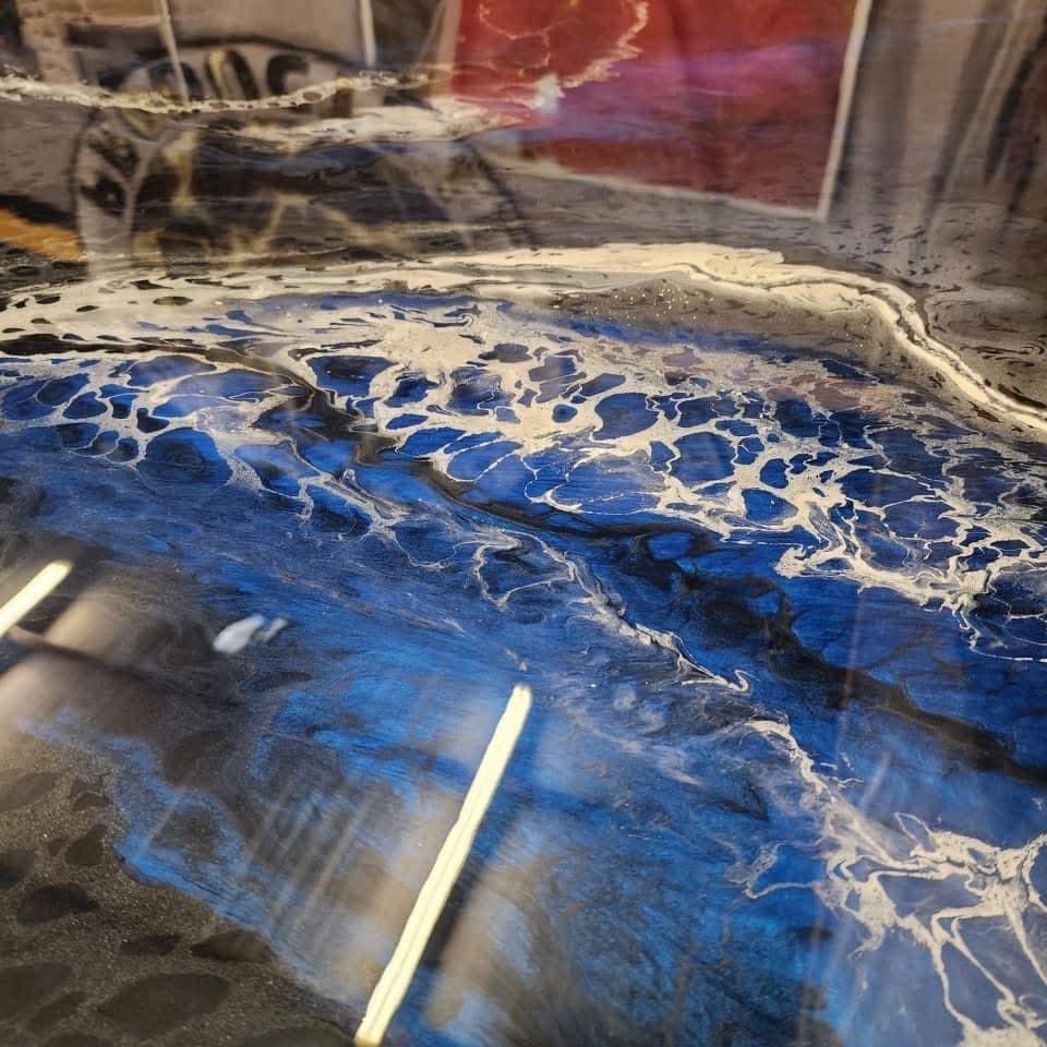 Epoxy resin countertop with blue and white swirling patterns, resembling waves.