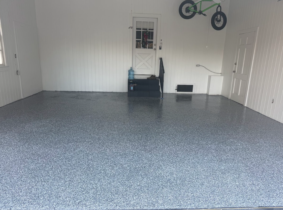 Garage interior with epoxy floor, white walls, small door, and bicycle.