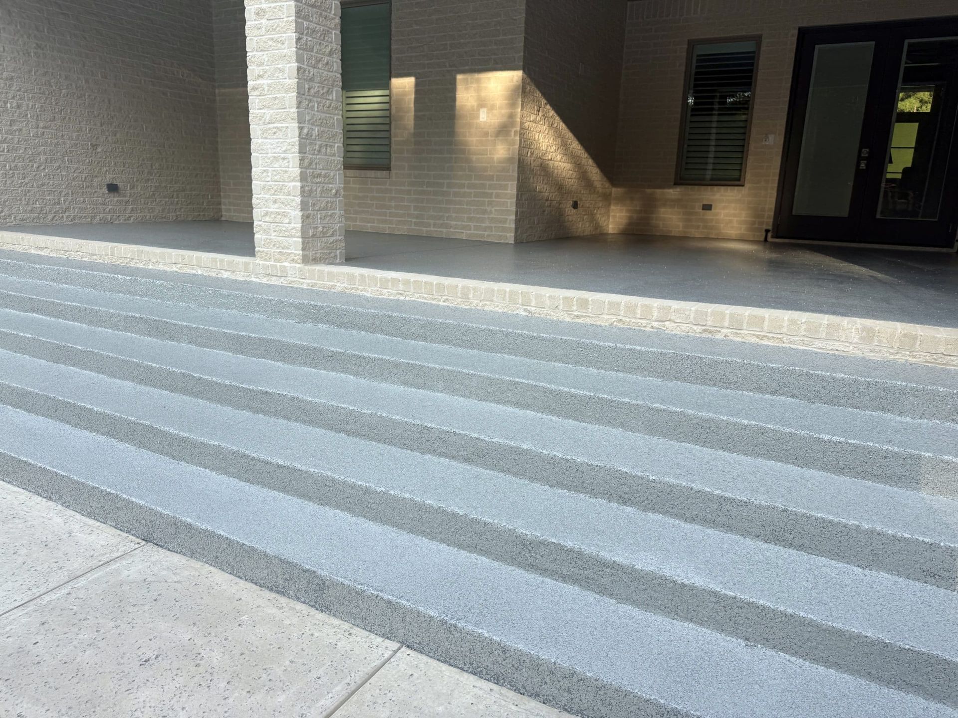 Grey concrete steps leading up to a covered patio.