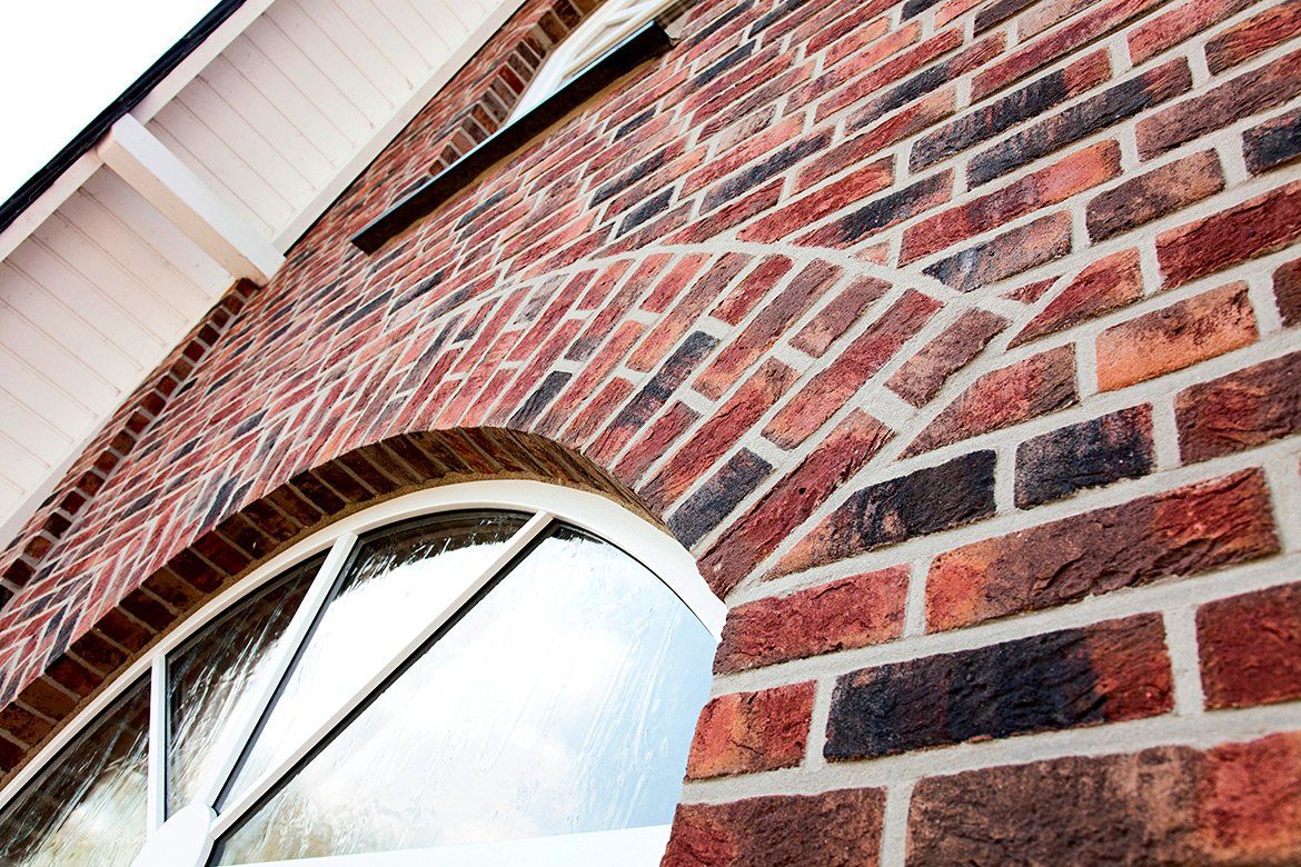 Brick building with arched window. Red and dark brown bricks, white trim.