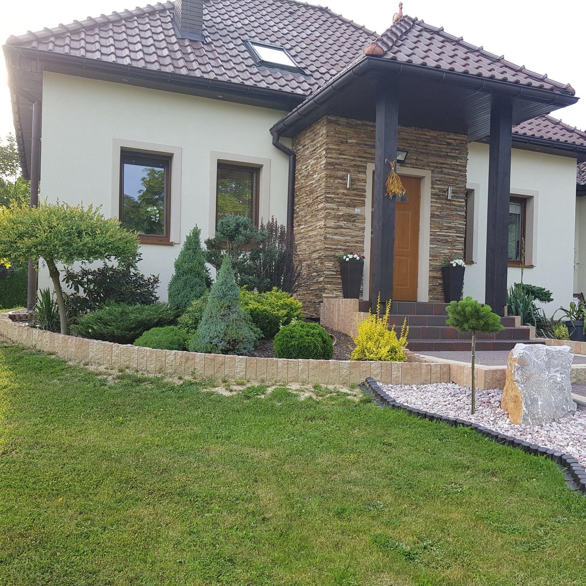 House with tan stucco exterior, brick accent, and landscaped yard.