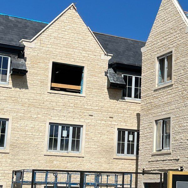 Stone building with gabled roofs, multiple windows, and a construction cart in front.