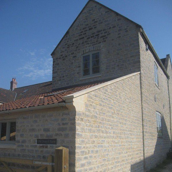 Stone building with two stories, red tile roof, and a blue sky backdrop.
