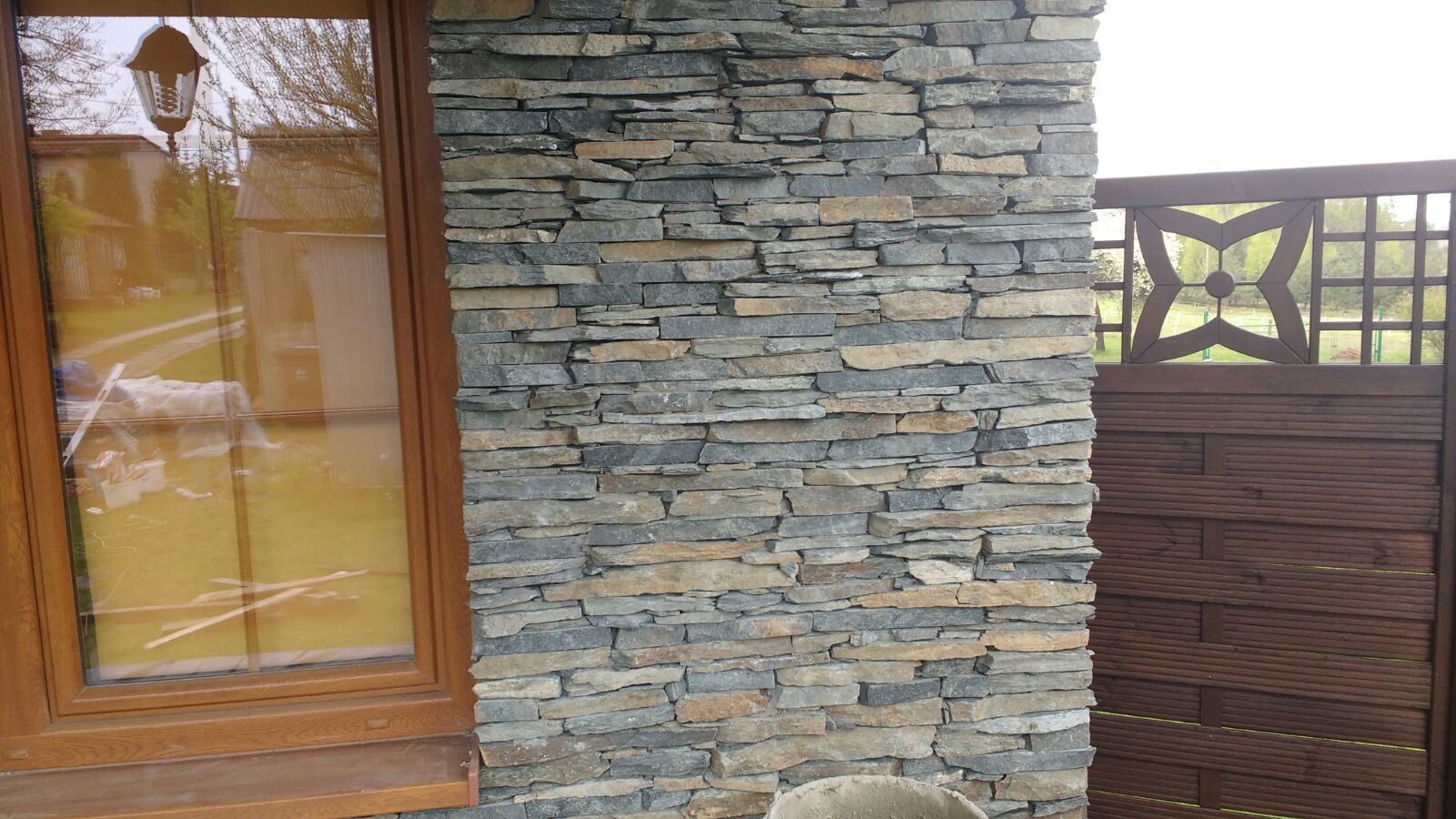 Stone facade wall next to a wooden window and fence with a decorative star design.