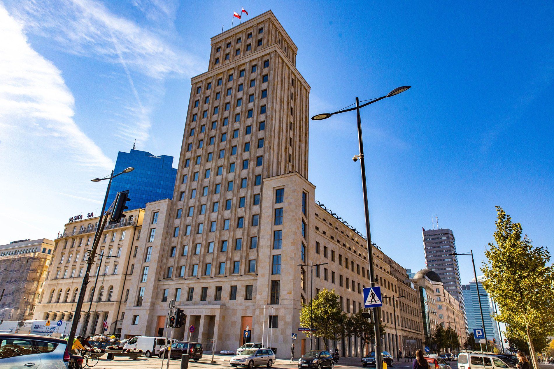 Tall beige building with many windows under a blue sky, Warsaw, Poland.