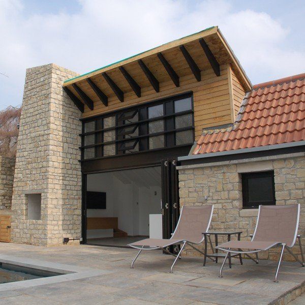 Modern house with stone facade, pool, and lounge chairs.