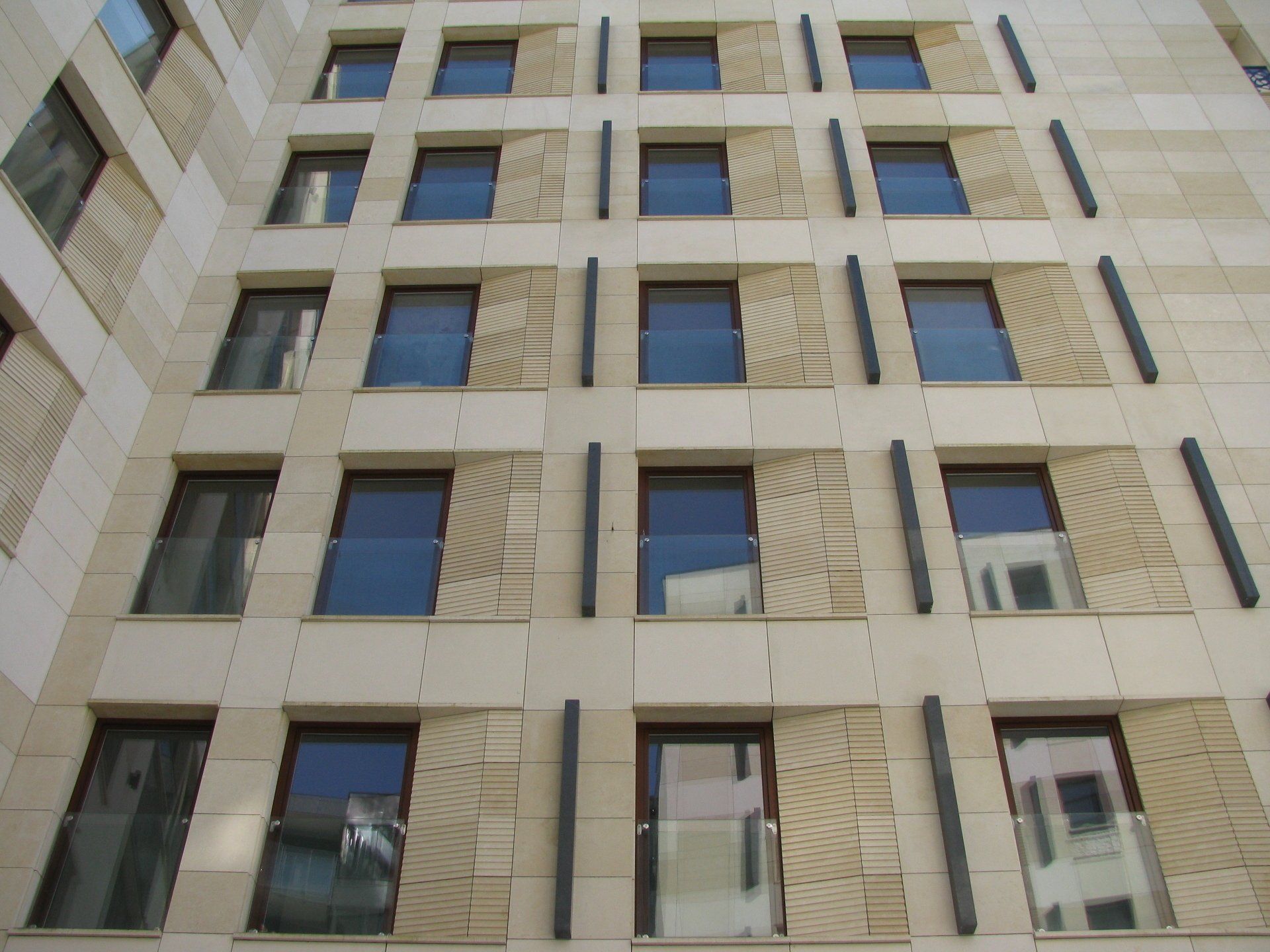 Beige stone building with rows of windows and vertical dark bars.