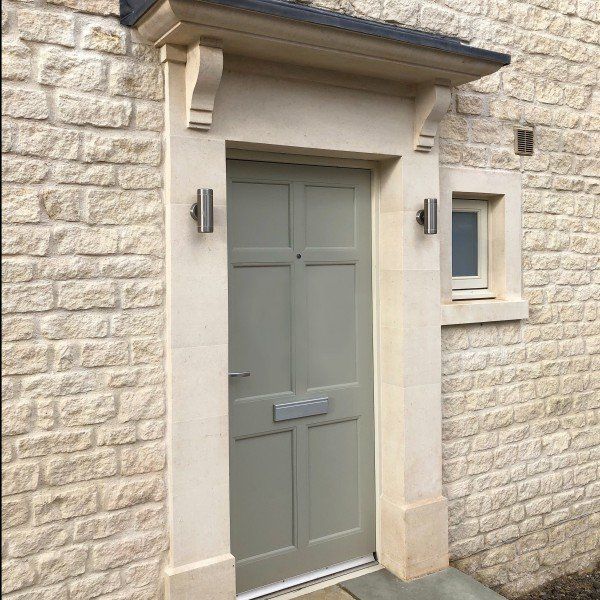 Beige stone exterior with sage green door, cream trim, and small window.