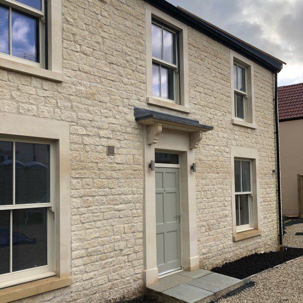 Beige stone house with gray door, windows, and trim; stone porch.