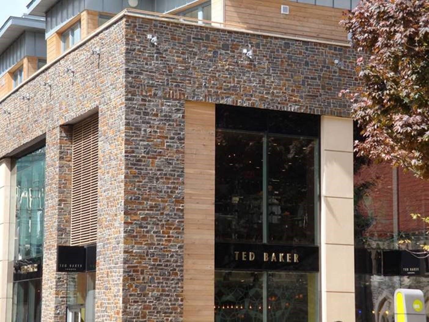 Ted Baker store exterior with brown brick facade, glass windows, and tan accents.