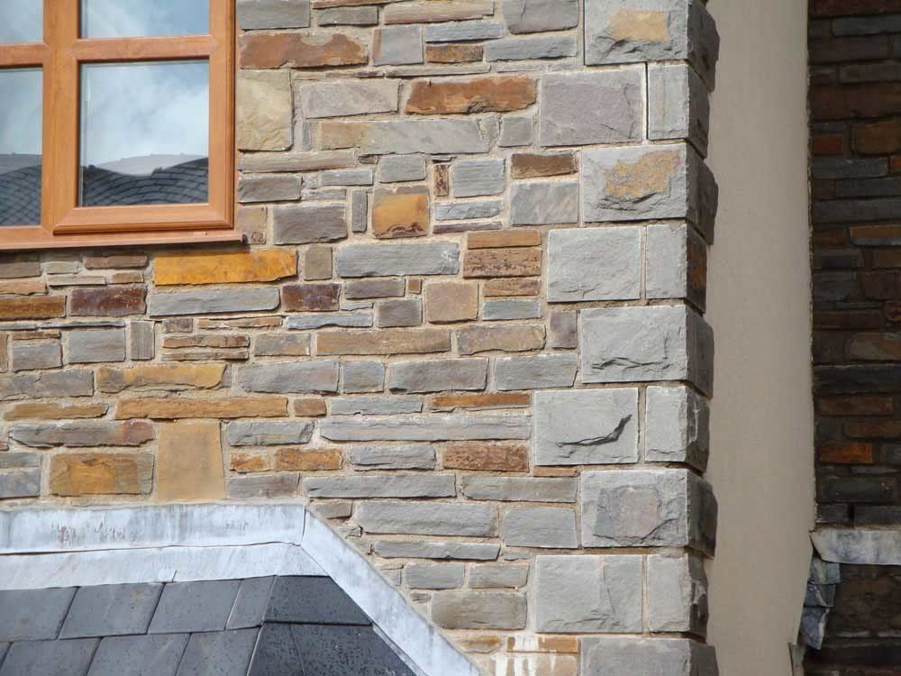 Stone exterior wall with varied rectangular blocks, and a window with a brown frame.