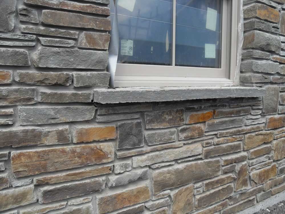 Stone exterior wall with window and gray window sill.