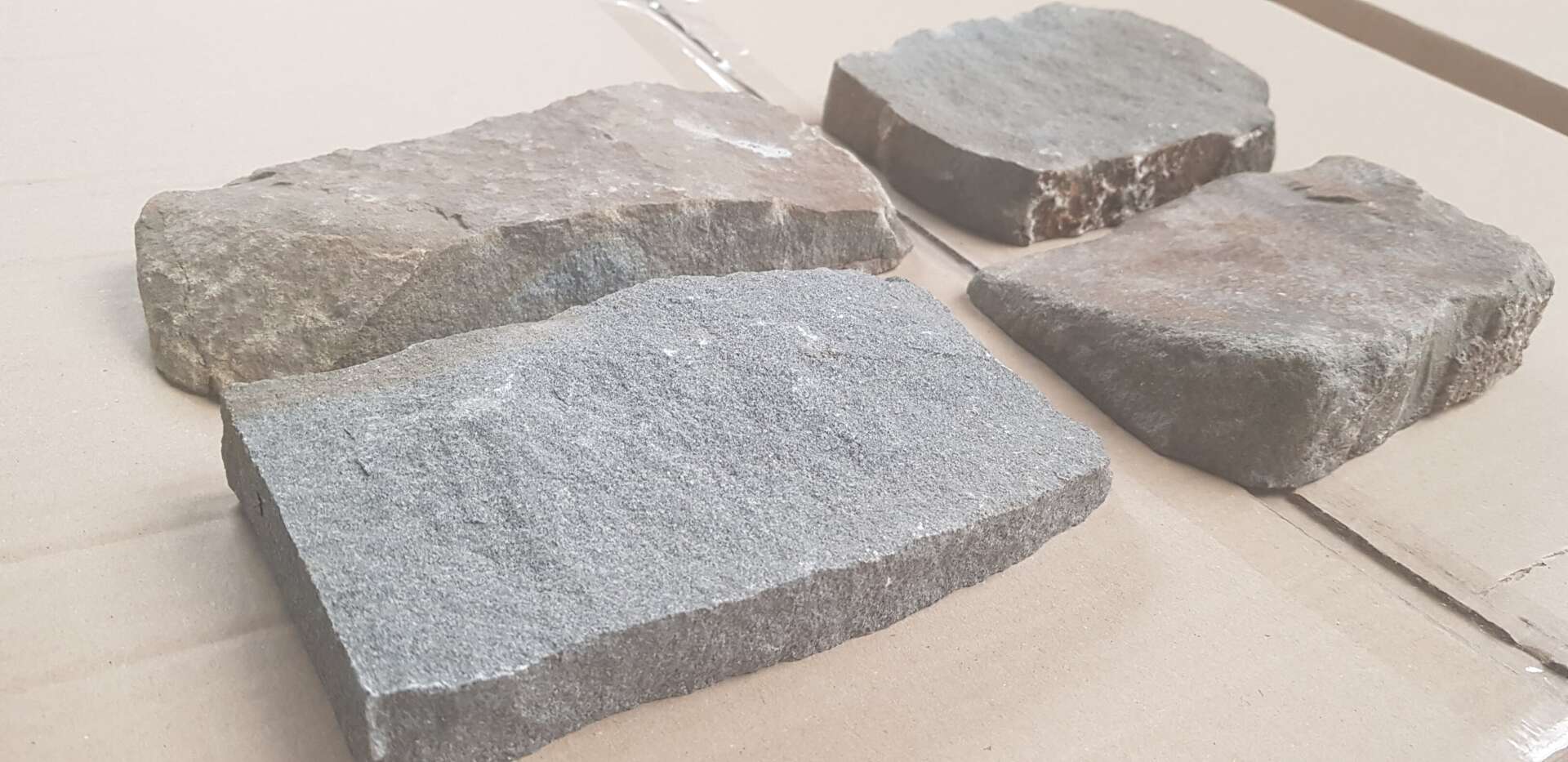 Four irregularly shaped stone pavers in varying shades of gray and tan.