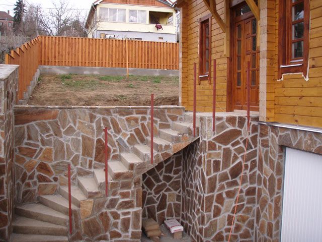 Stone steps leading to a wooden house with a fence in the background.