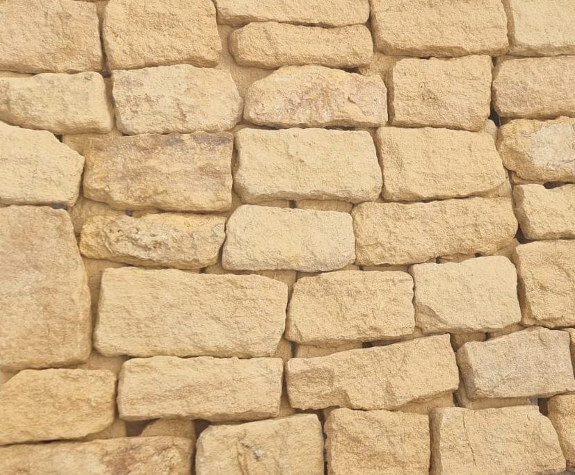 Beige stone wall with irregular rectangular blocks.