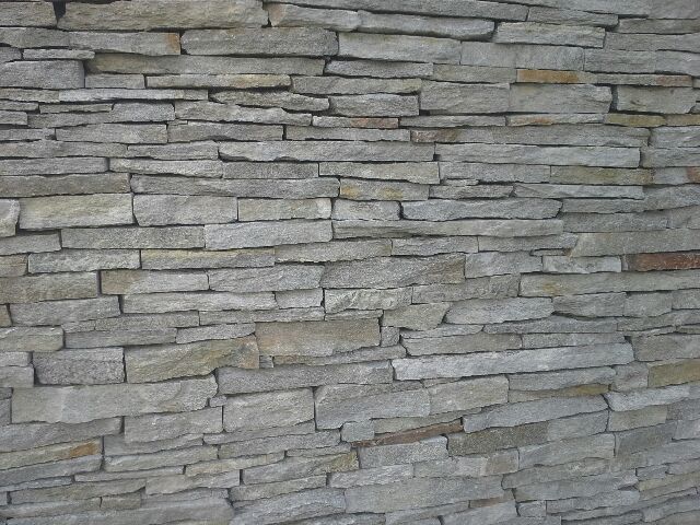 Stone wall composed of horizontal, irregular rectangular stones in shades of gray.
