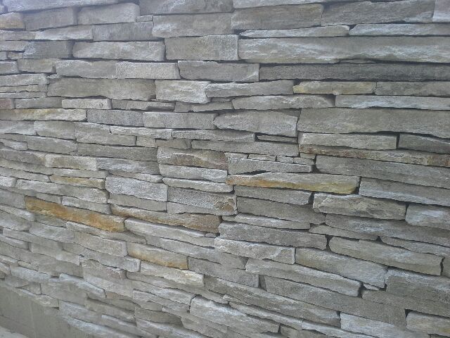 Stone wall with rectangular, gray and tan stones.