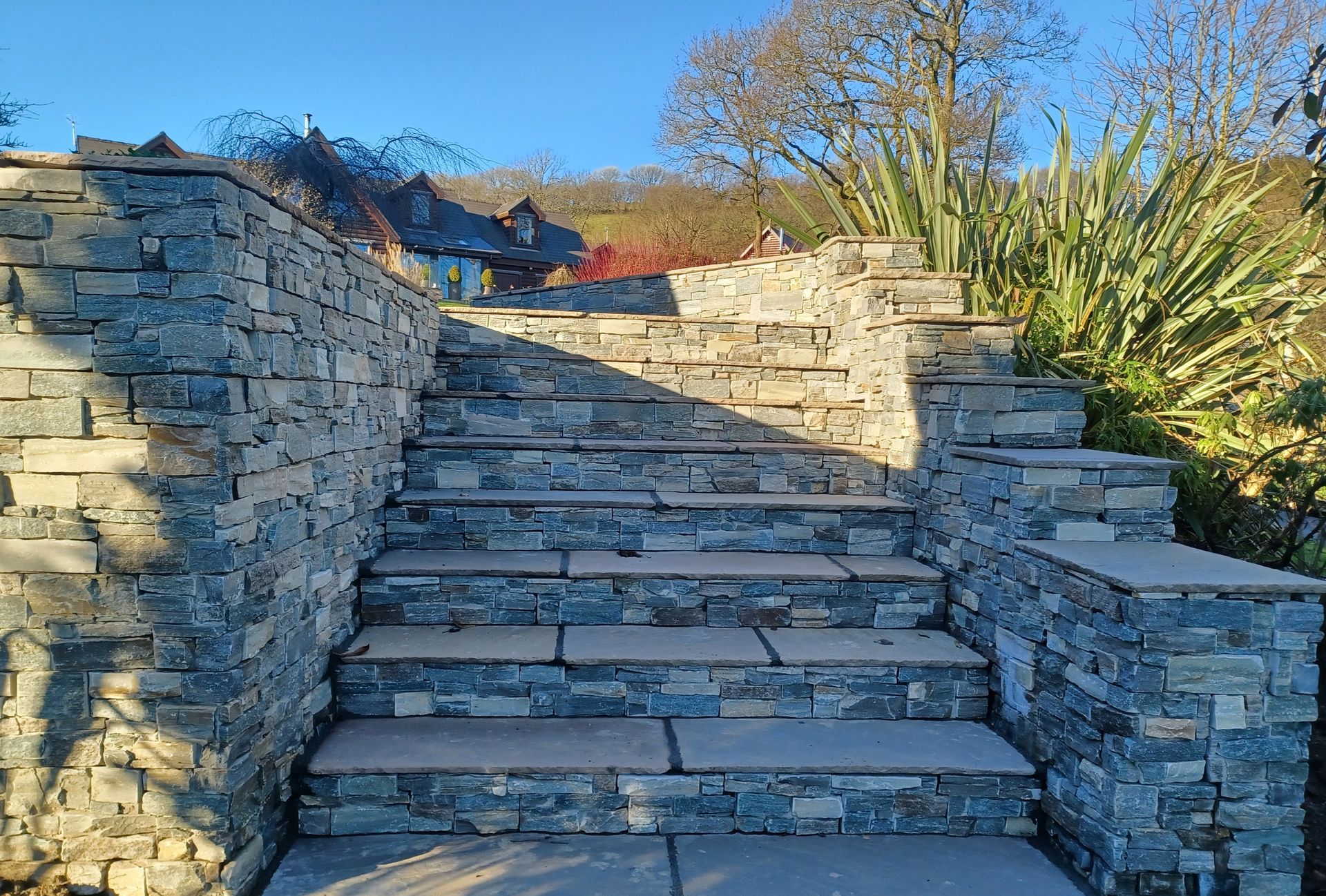 Stone steps leading up, framed by stone walls, sunny outdoor setting.
