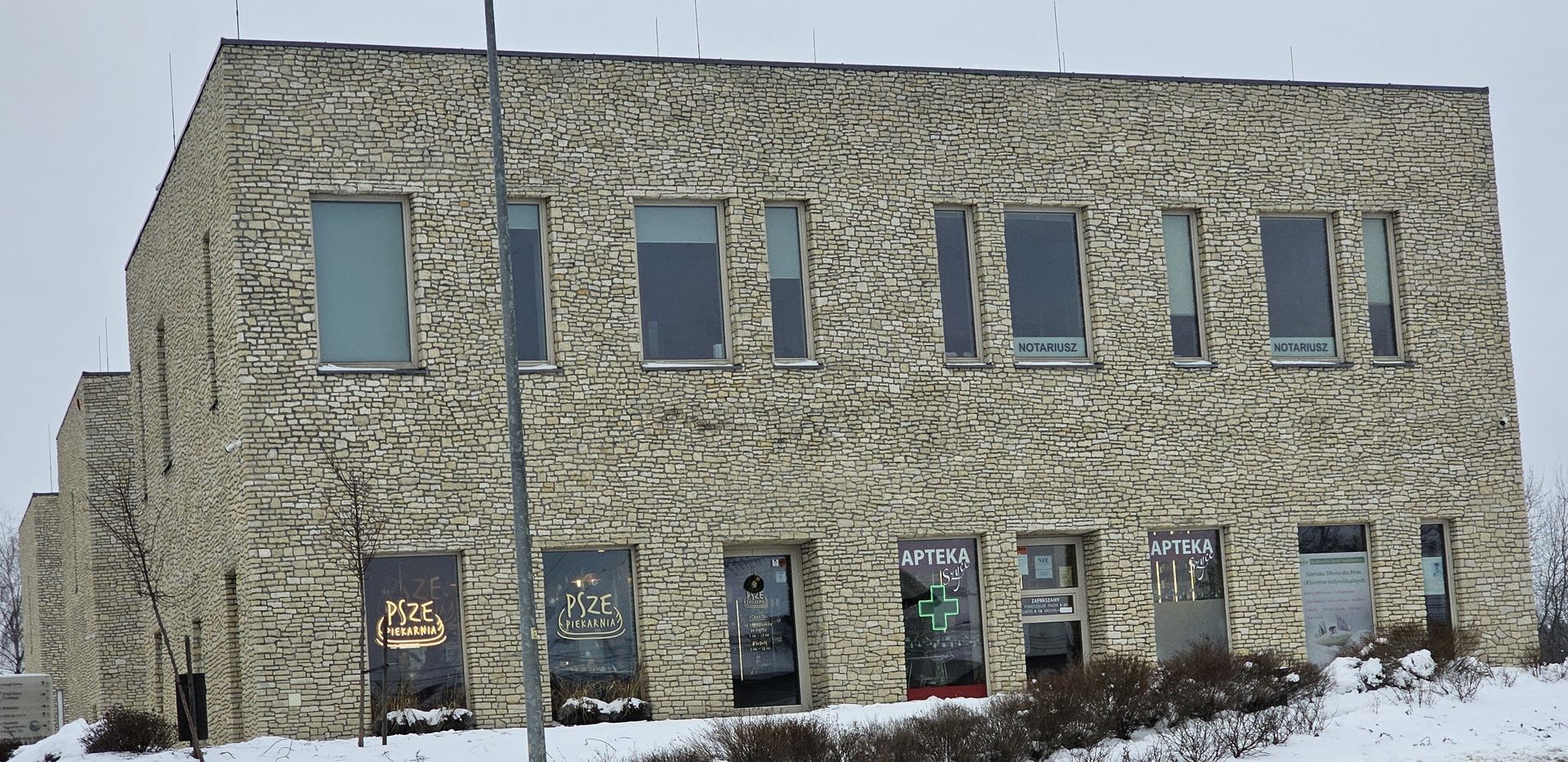 Stone building with multiple windows; snow on the ground; overcast sky.