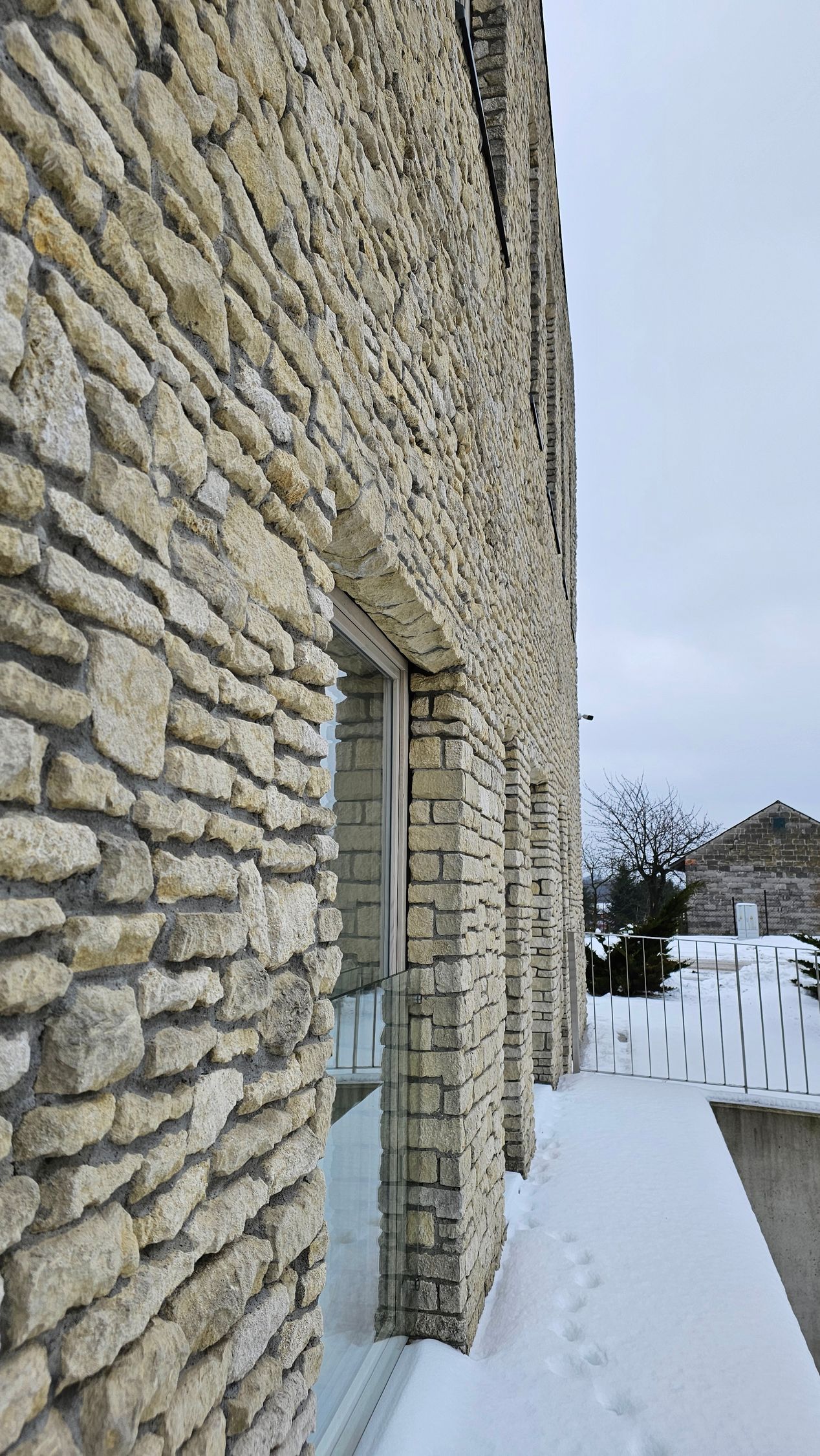 Stone building exterior with empty window frames, covered in snow.