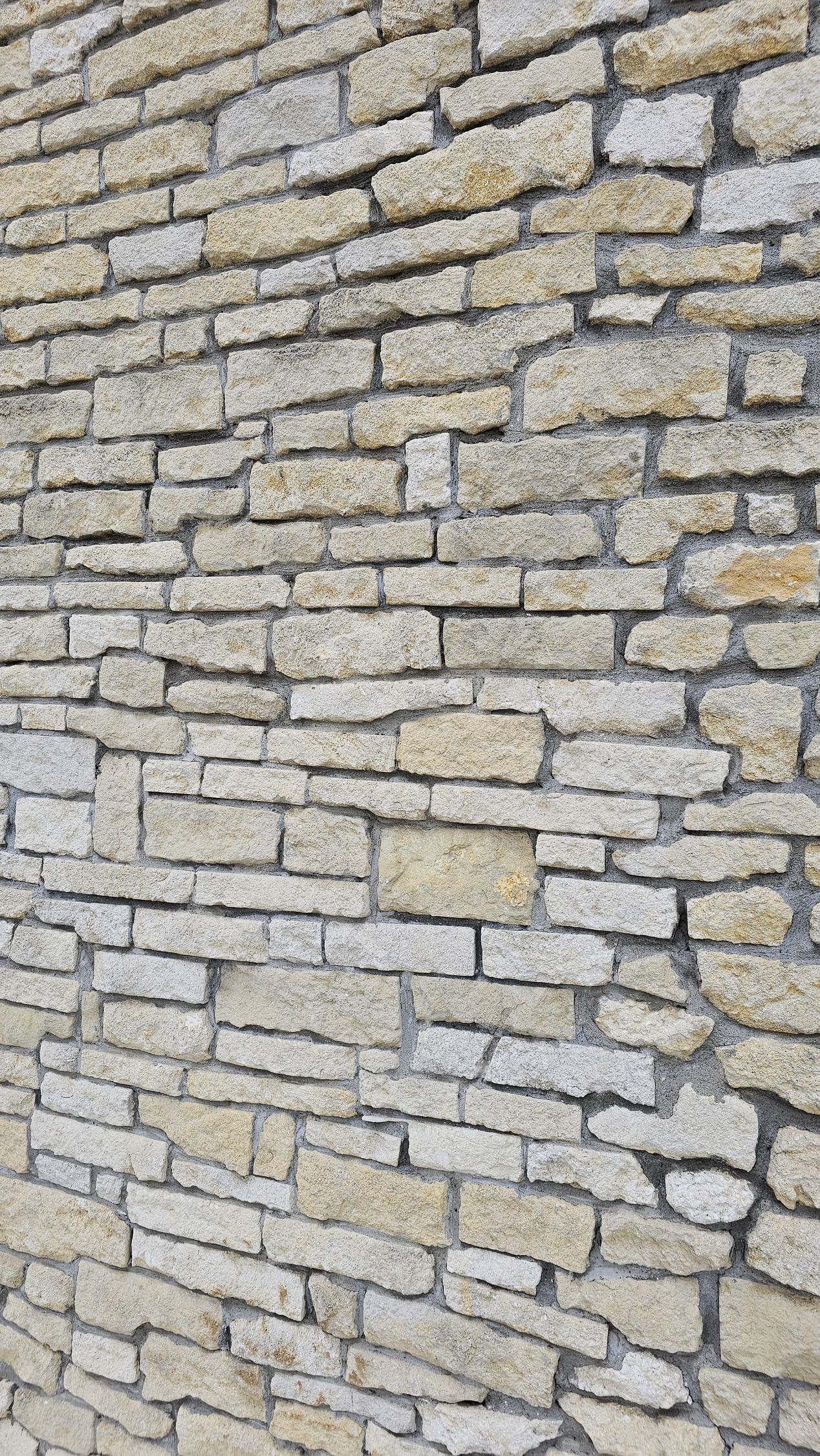 Stone wall composed of rectangular, light-colored blocks with gray mortar.