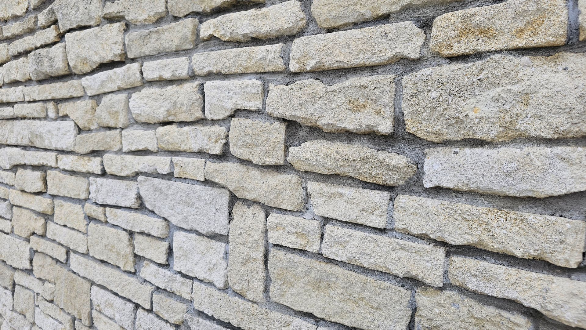 Stone wall with irregular, light-colored blocks and gray mortar.
