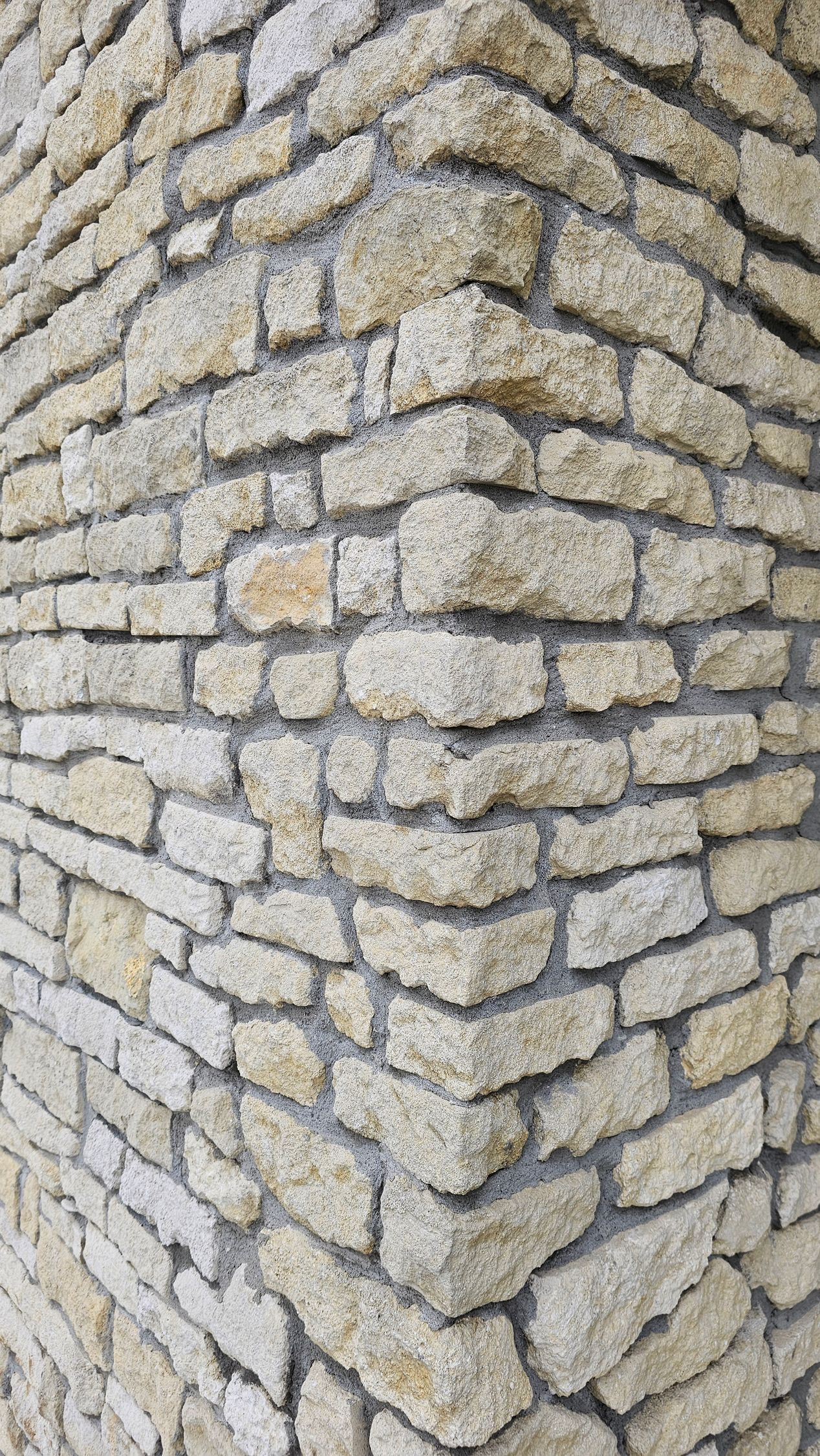 Corner of a stone wall, beige stones mortared together.