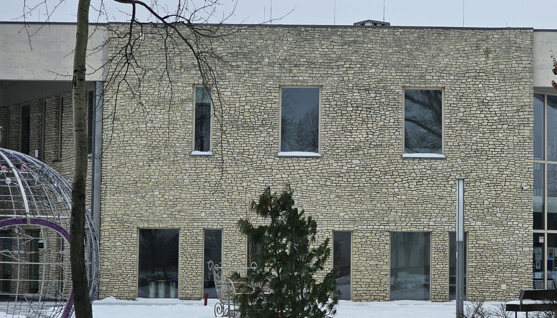 Brick building with several rectangular windows; snow on the ground and trees.