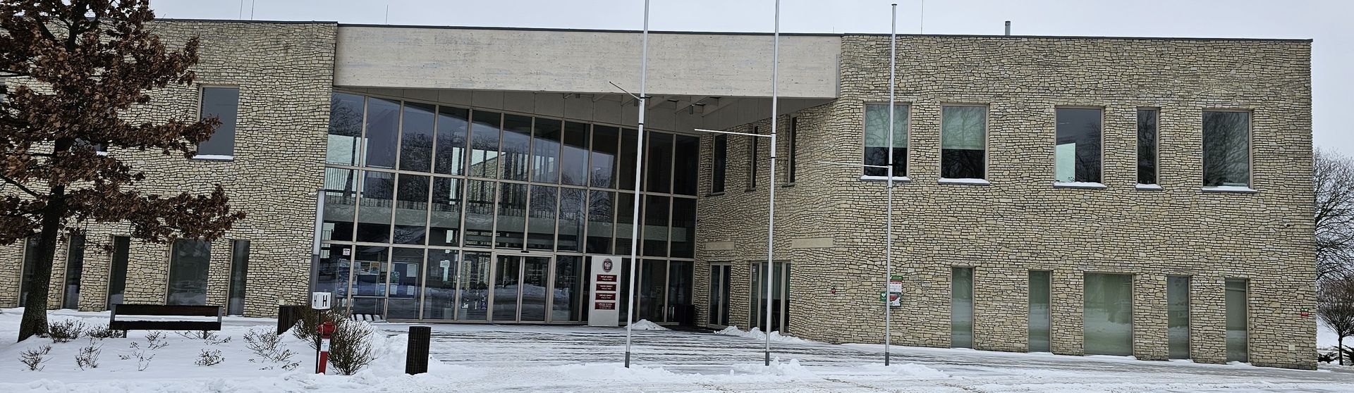 Stone building with large windows and snow-covered ground.
