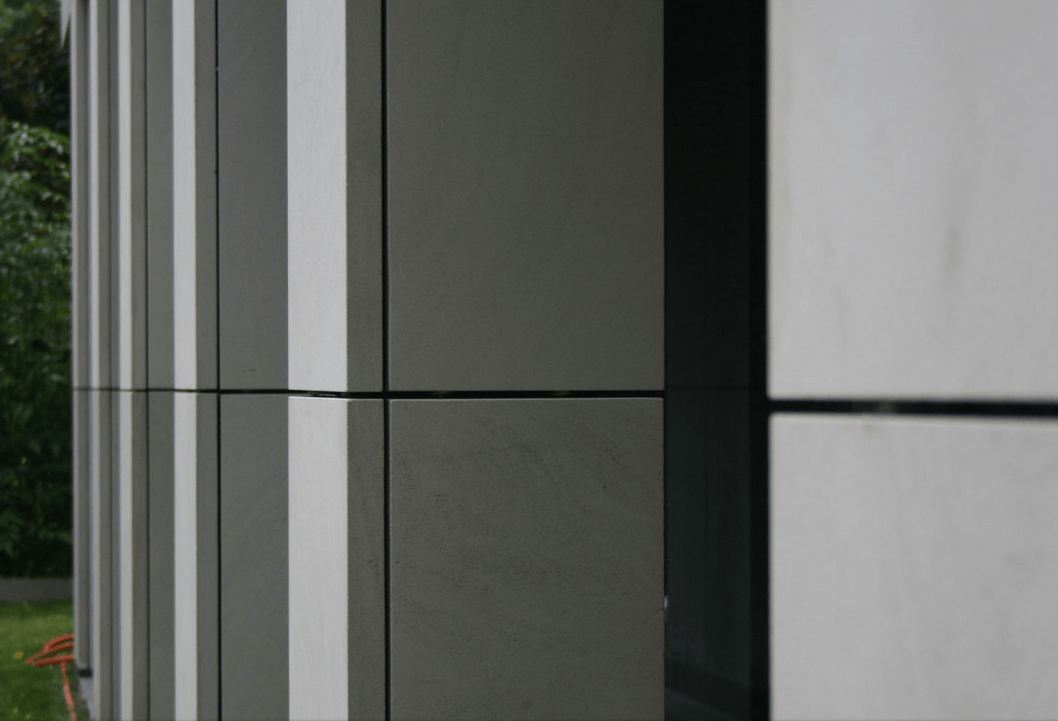 Exterior of a building with alternating gray, white, and dark panels, with horizontal seam lines.