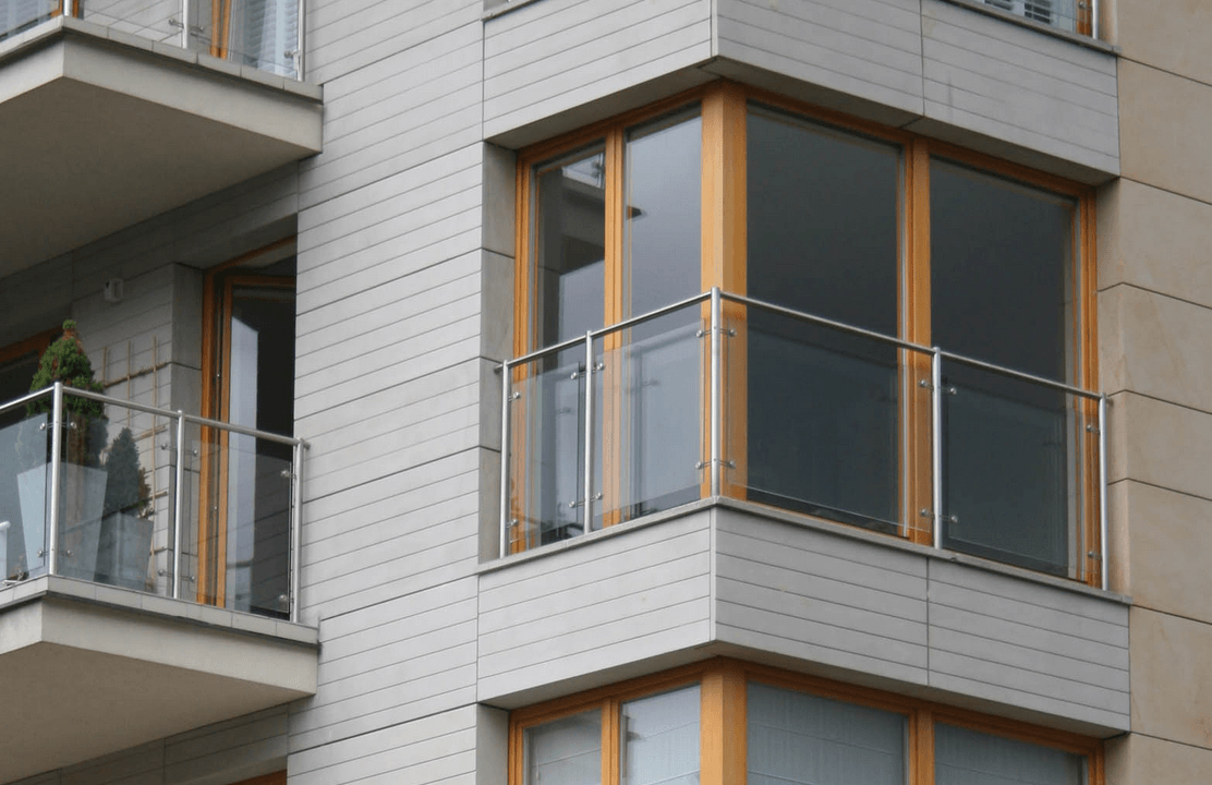 Balconies on modern building with glass railings and wood frames.