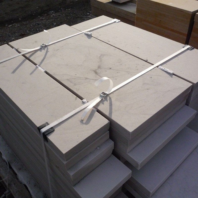 Pallet of light-colored rectangular stone slabs secured with white straps.
