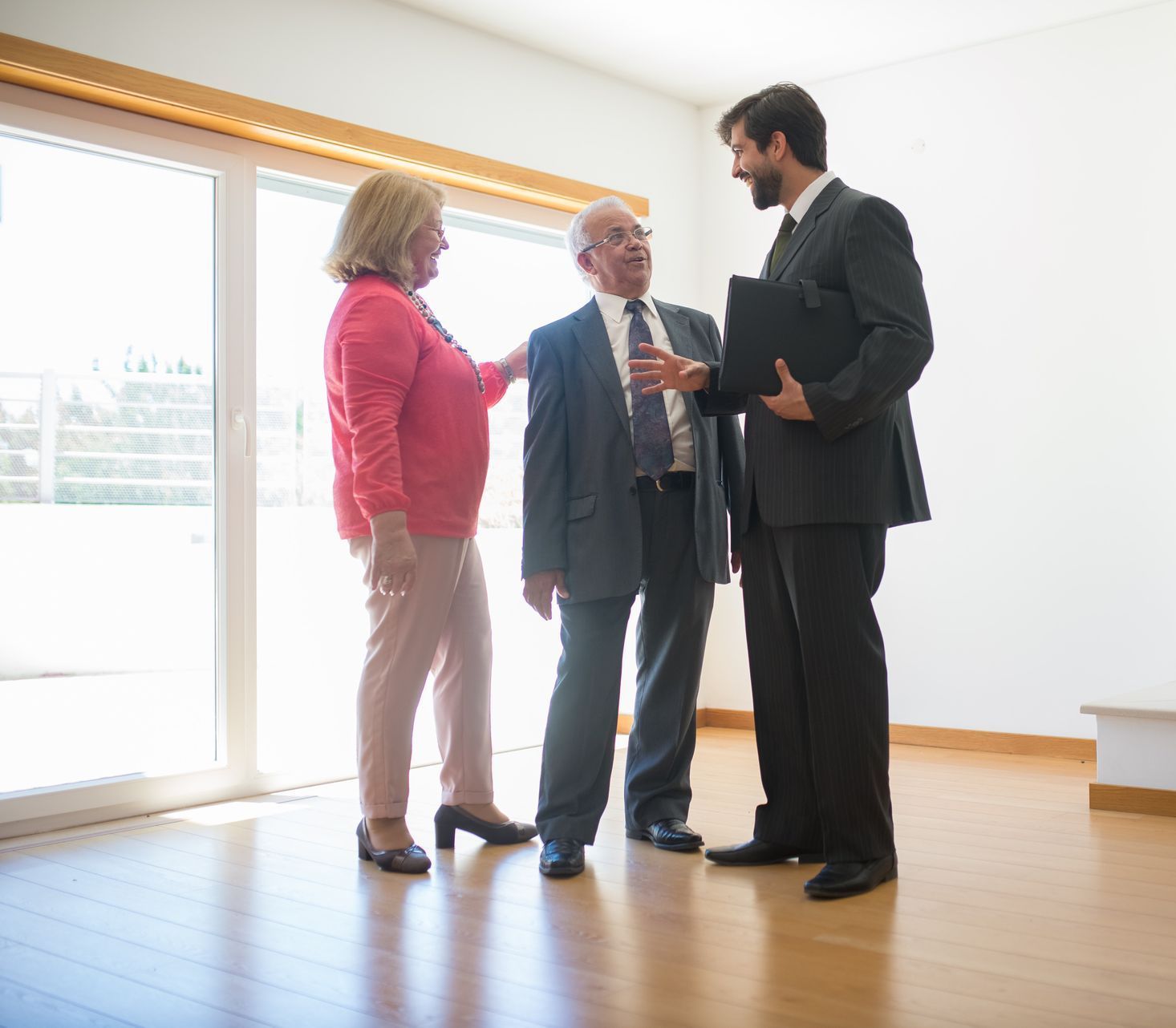 A man in a suit is talking to two people in an empty room.