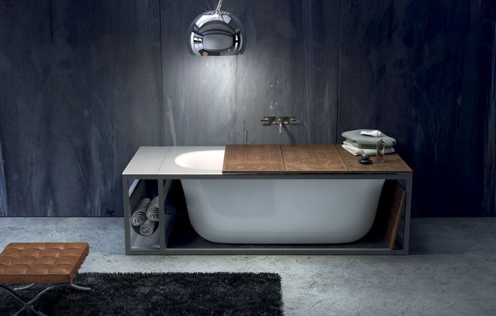 Bagno moderno e minimalista con vasca bianca, piano in legno, pareti scure e specchio rotondo.