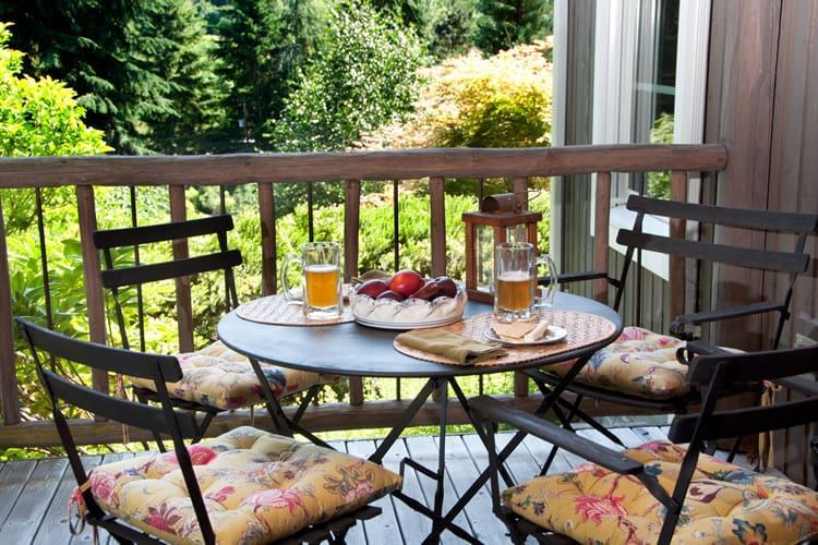 A table and chairs on a balcony with a view of trees