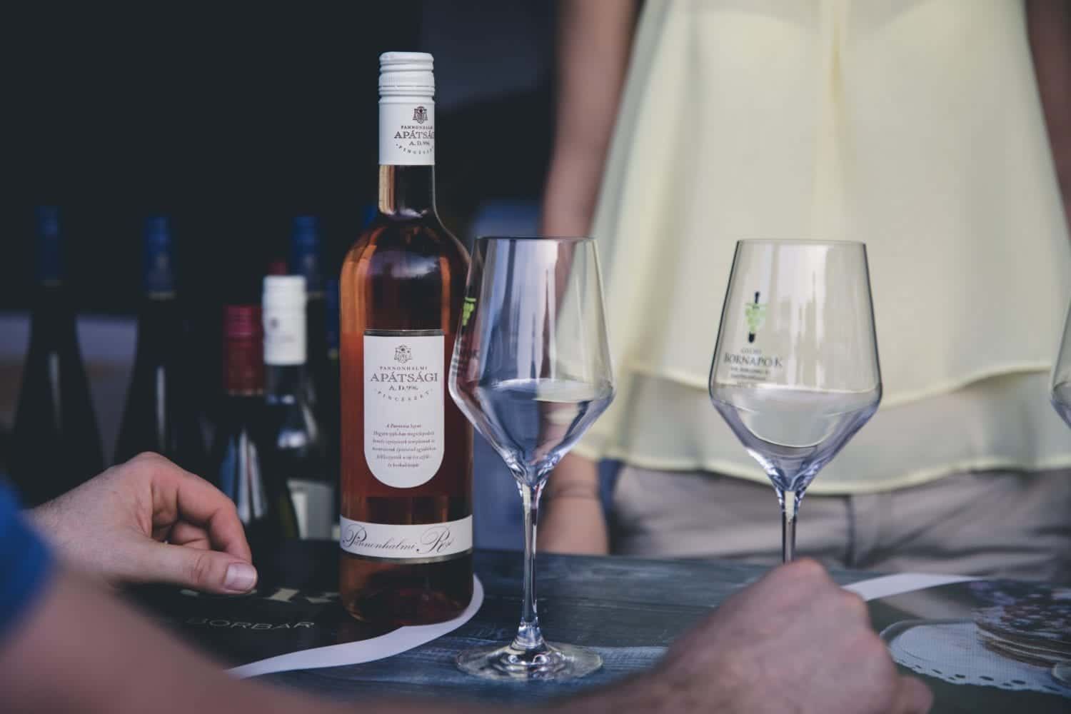 A bottle of wine is sitting on a table next to two wine glasses.