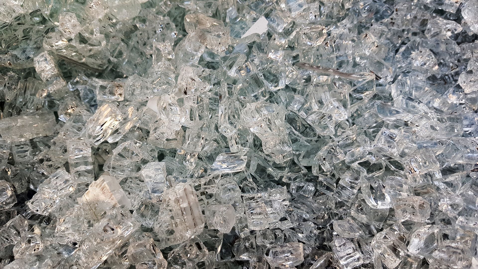 A close up of a pile of broken glass on the ground.