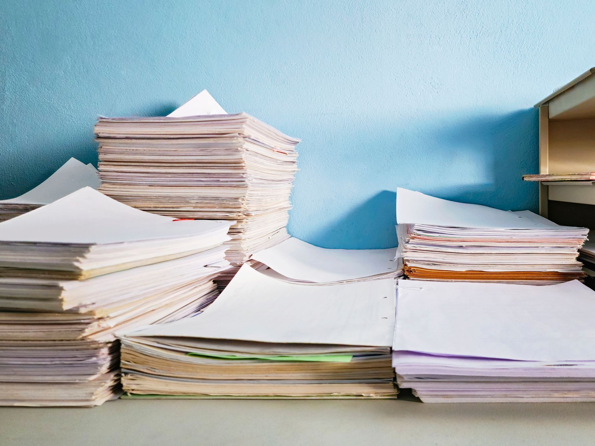 A stack of papers on a table with a blue wall in the background