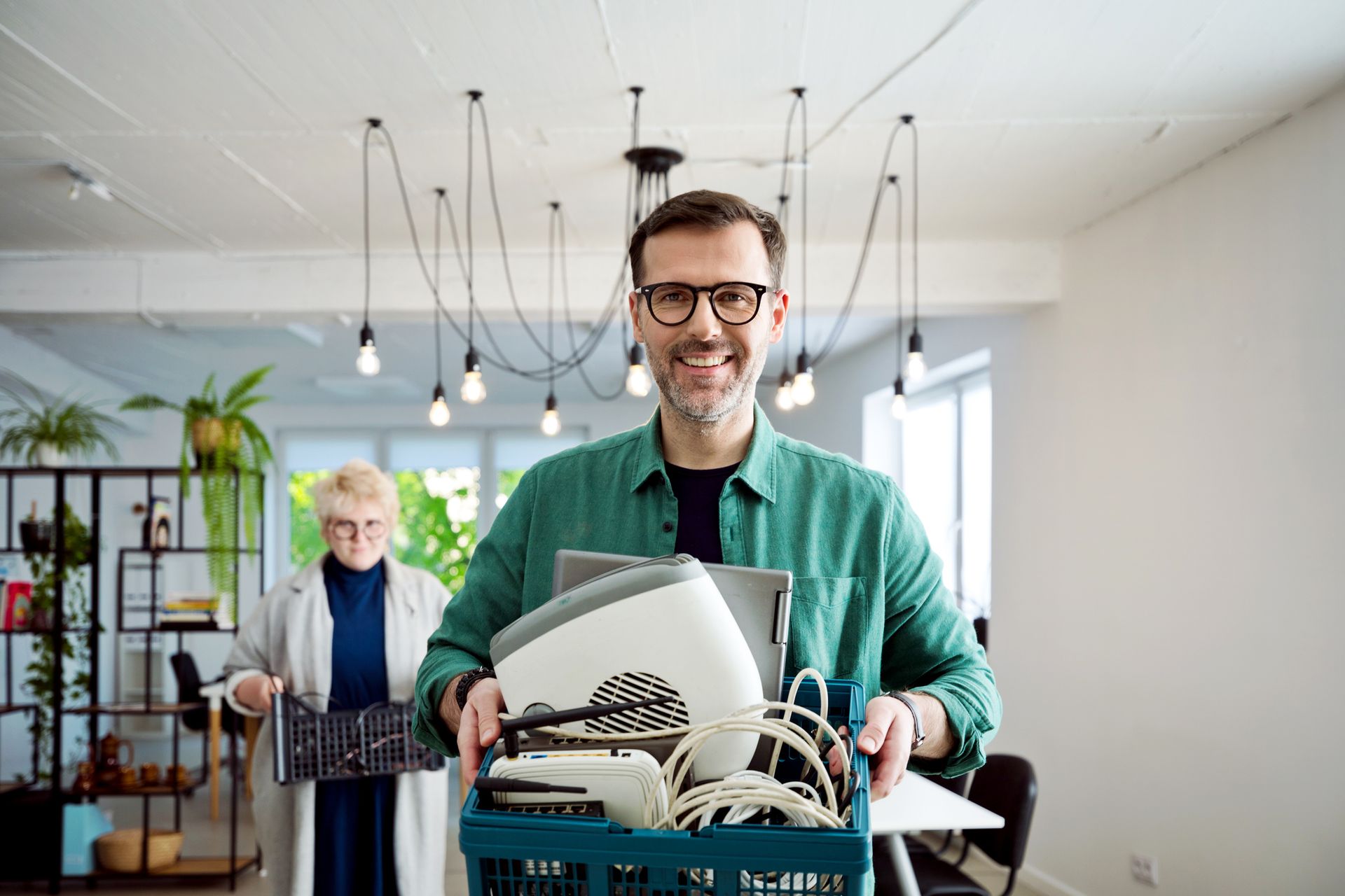 A man is carrying a box full of old electronics.