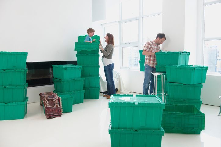 A family is moving into a new home and stacking green boxes on top of each other.
